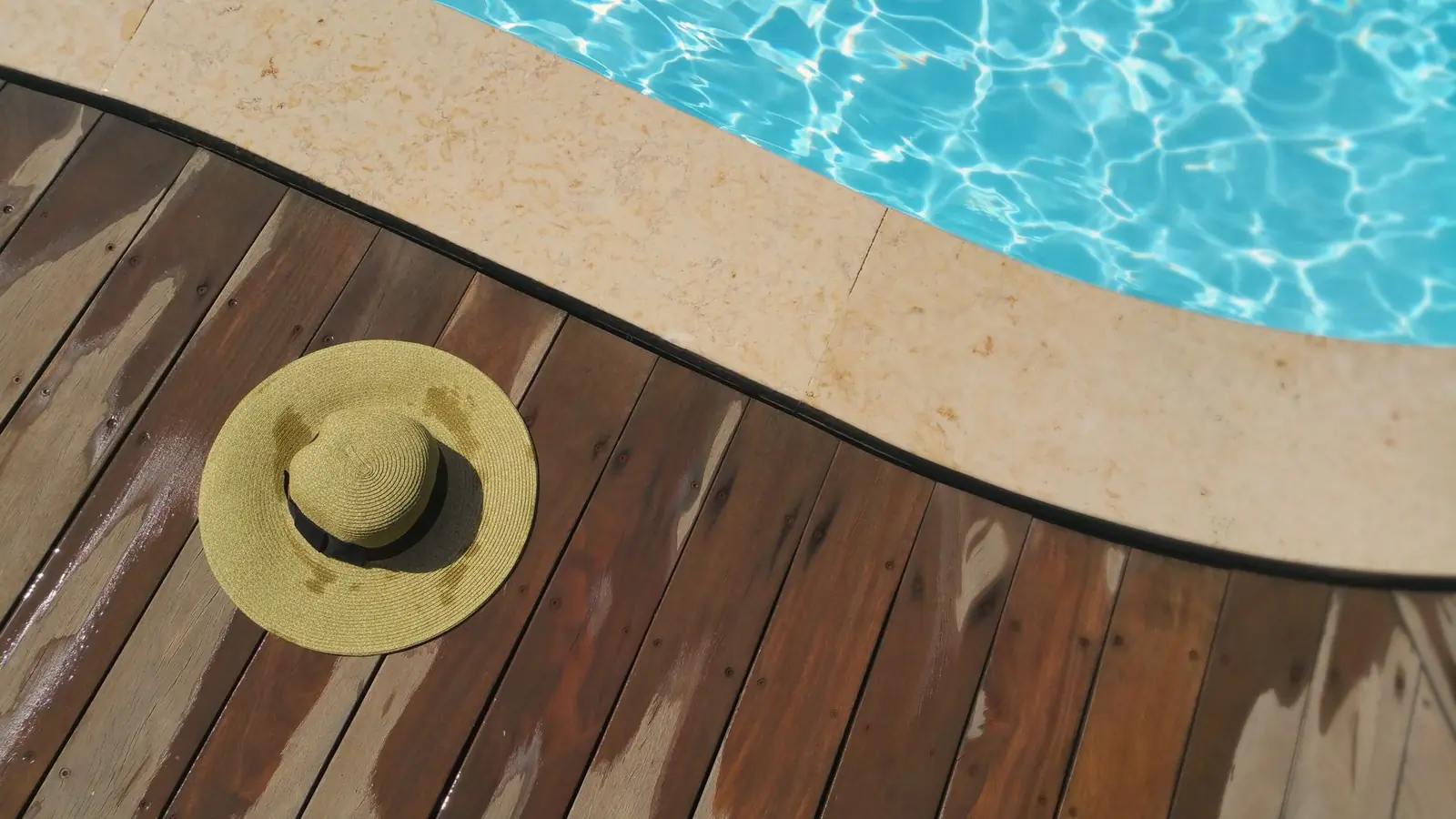 Timber decking meeting stone coping at the edge of a pool